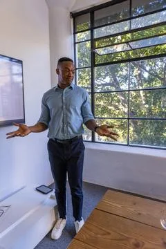 African american man gesturing, explaining spreadsheet data on flat screen in Stock Photos