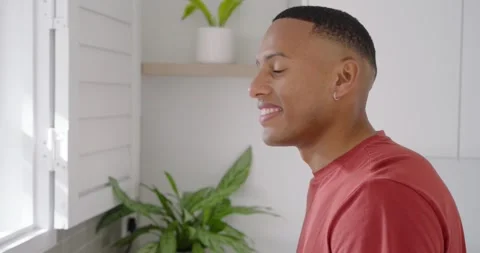 African American man glancing from kitchen window, shifting to camera and Stock Footage 342843741