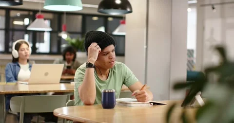 African American man in hat pausing tapping pencil writing notebook and sorting Stock Footage 344340475