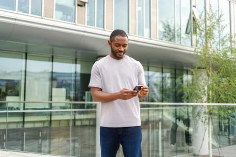 African american man holding smartphone touch screen typing scroll page on urban Stock Photos