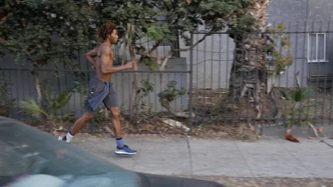 African American man jogs through poor neighborhood. Stock Footage