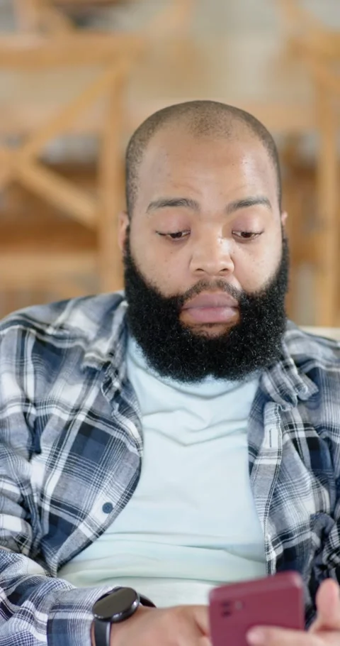African American man looking at red phone, scrolling, reacting to content on Stock Footage 345219340