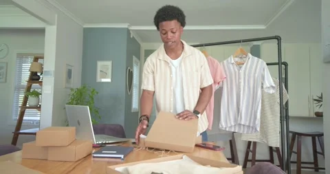 African American man packing boxes at home, opening box, tying twine, attaching Stock Footage 339652109