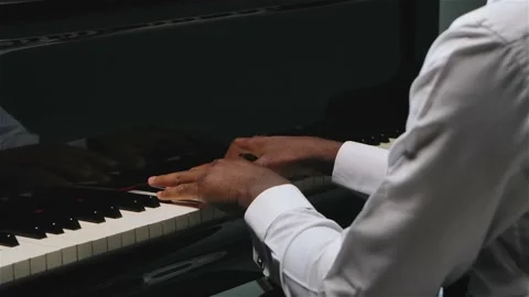 An African American man plays gentle classical music on the grand piano with Stock Footage 139667849