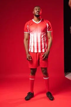 African American man posing in studio on red backdrop, wearing striped jersey, Stock Photos