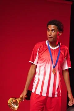 African American man posing in studio red backdrop, in jersey and blue medal, Stock Photos