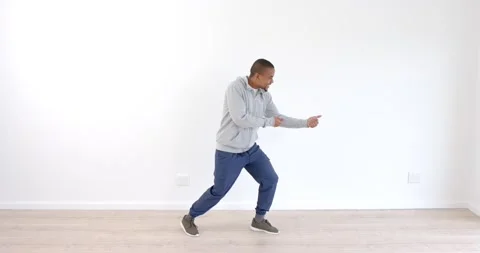 African American man practicing dynamic dance moves in minimalist studio space Stock Footage 346597567