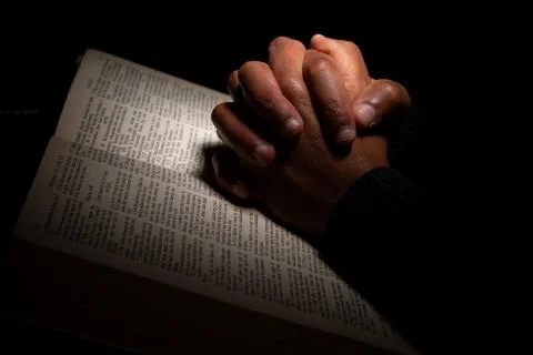 African American Man Praying with Hands on Top of the Bible. Stock Photos