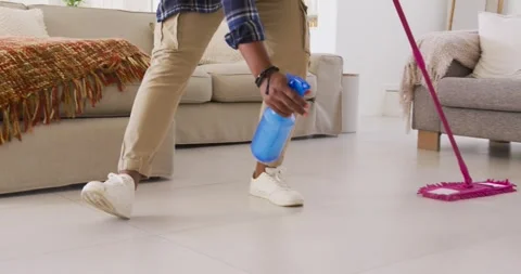 African American man preparing blue spray bottle, mopping tile floor with pink Stock Footage 341241936