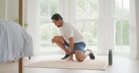 African American man progressing squat to seated stretch for mobility on mat Stock Footage 338064371
