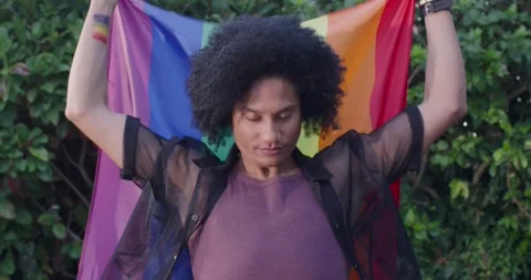 African American man pulling open sheer shirt spreading rainbow flag overhead Stock Footage 337239438