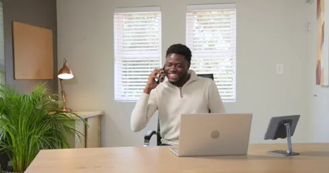 African American man in pullover working at laptop hearing phone buzzing, Stock Footage 343888900