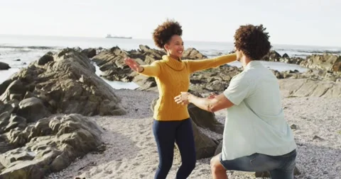 African american man putting a ring on his girlfriend's finger on the rocks near Stock Footage 337159243