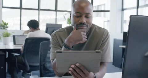 African American man reading tablet with folio case, tapping, thinking over work Stock Footage 345589365