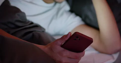 African American man receiving message, reading red phone in bed, frowning, Stock Footage 339721647