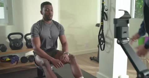 African American man rowing checking watch, sipping water while friend coaching Stock Footage 340968930
