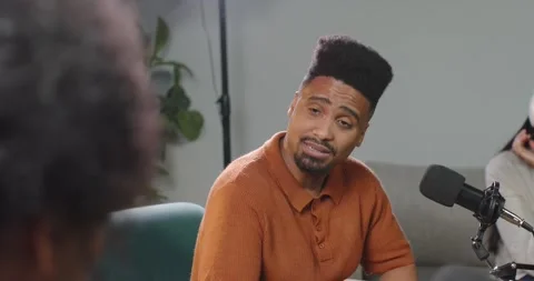 African American man in rust polo reacting to senior speaker, speaking into mic Stock Footage 344964206