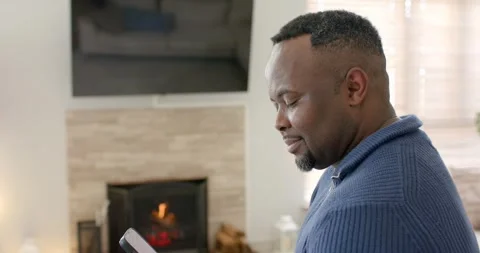 African American man scrolling tablet content in living room for fun and Stock Footage 335986287
