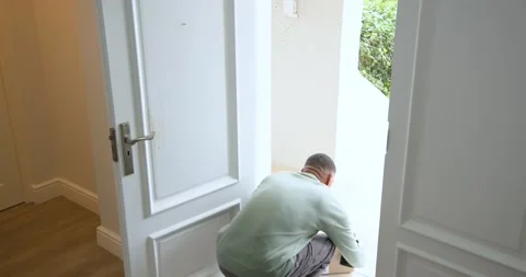 African American man seeing parcel at door opening it lifting parcel checking Stock Footage 342363374