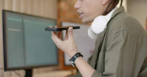 African American man in shirt checking laptop, grabbing phone, using speaker at Stock Footage 340148060