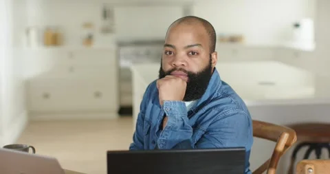 African American man sitting at kitchen table in denim shirt reading message on Stock Footage 338064290