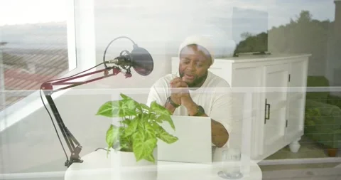 African American man sitting at small round table, recording into boom mic by Stock Footage 337933208