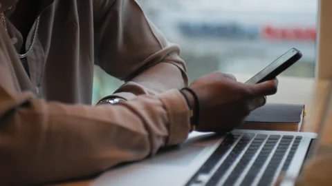 An African-American man is sitting at a table, holding a phone in his hand Stock Footage 262629366