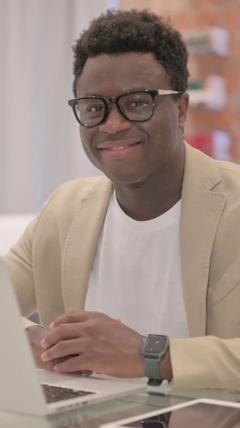 African American Man Smiling at Camera while Working on Laptop, vertical video Video stock 328566338