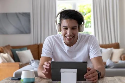 African American man smiling using tablet on white stand at wooden table wearing Stock Photos