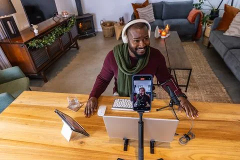 African American man speaking to camera in studio wearing sweater, using phone Stock Photos