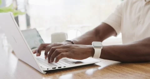African American man starting work at table, typing on white laptop, wearing Stock Footage 343367937