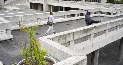 African American man stretching hamstring on roof as walker carrying smartphone Stock Footage 341851608