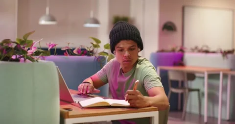 African American man at table in study lounge checking laptop, typing and Stock Footage 335514406