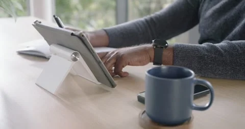 African American man tapping tablet to reference content and writing in notebook Stock Footage 337287948