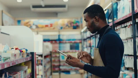 African American man types on smart tablet looking at goods on store shelves Video stock 312868909