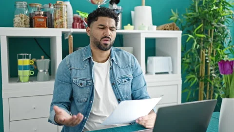 African american man using laptop reading document looking upset at dinning.. Stock Footage 239807554