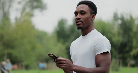 African american man using smart phone inside city park after exercising outdoor Stock Footage 159887251