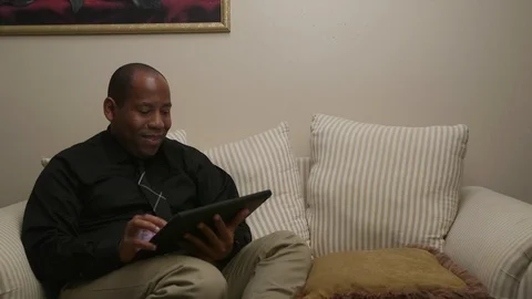 African American Man Using Tablet While Sitting on Sofa Stock Footage 110907773