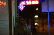 African-American Man Wearing Hoodie Under Neon Sign At Night Stock Photos