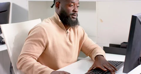 African American man working on computer in office, smiling and focused on Stock Footage 346219189