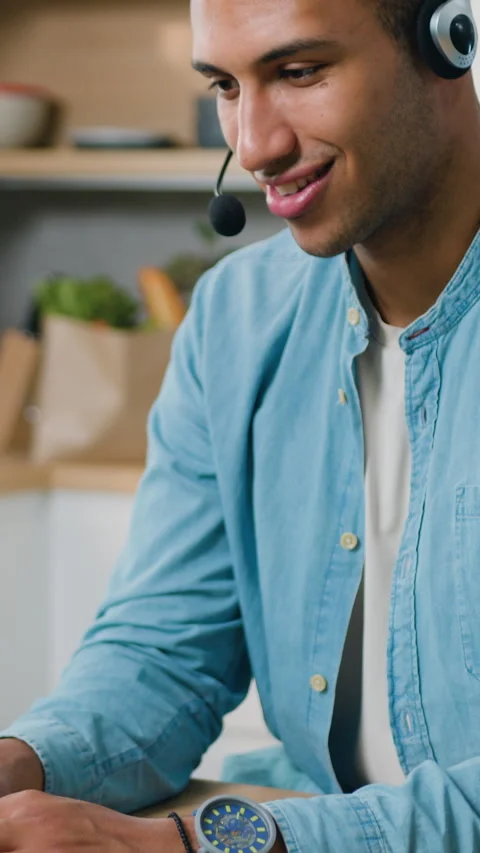 African American man working at kitchen using laptop and earphones. Smiling youn Stock Footage 333514994
