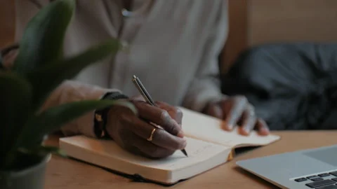 An African American man is writing in a notebook. Close up. Stock Footage 268987397