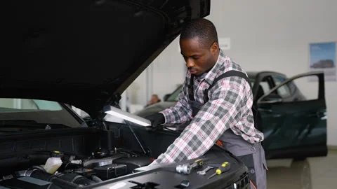 African American mechanic inspecting engine with lamp before repair Stock Footage 300608909