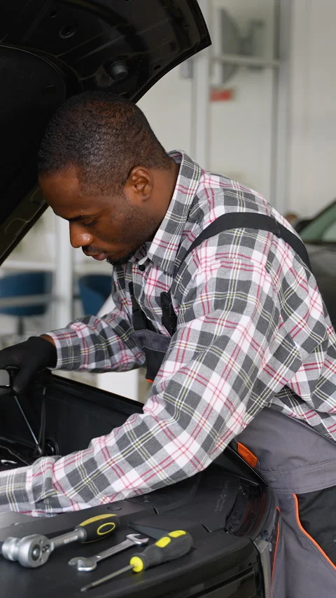 African American mechanic inspecting engine with lamp before repair Stock Footage 300613876