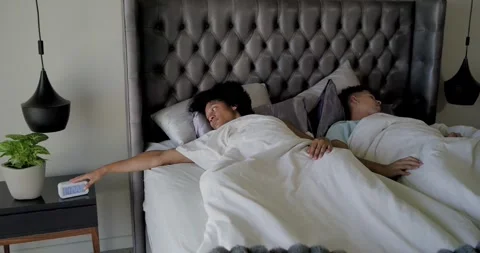 African American men on bed, left man muting ringing alarm clock, getting up, Stock Footage 344949486