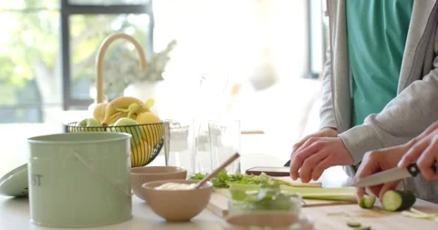 African American men glancing then chopping cucumber on board at island, making Stock-Footage 344656113