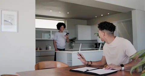 African American men at kitchen table man finishing call walking over showing Stock Footage 340774137