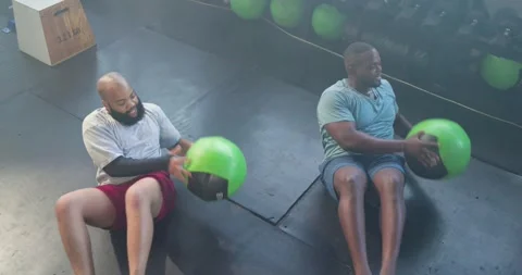 African American men starting doing core twists on mats in gear passing green 스톡 동영상 340070161
