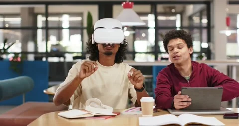 African American men at study table one donning white VR headset gesturing as Stock Footage 343515581