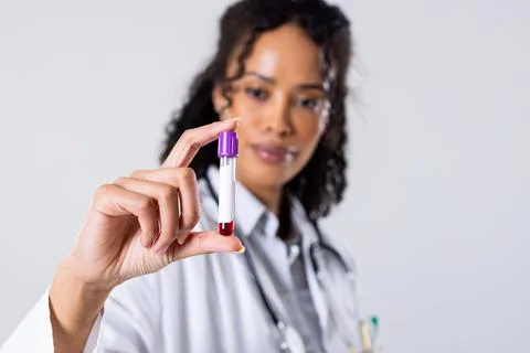African american mid adult female doctor holding blood sample in test tube Stock Photos